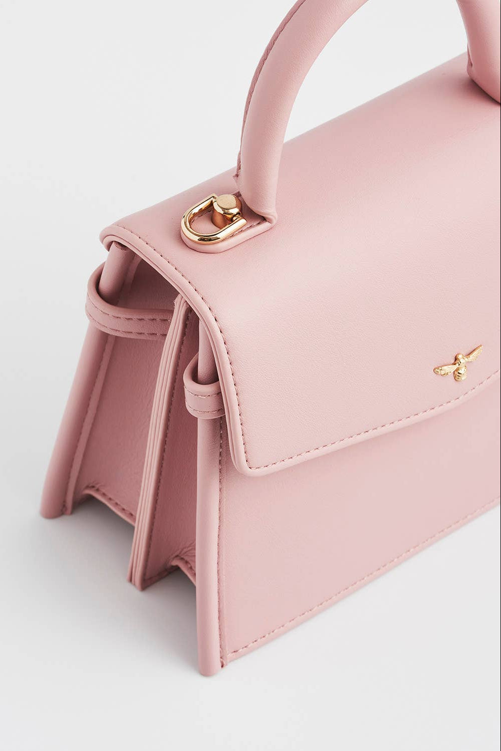 Pink handbag with gold accents on a light gray background