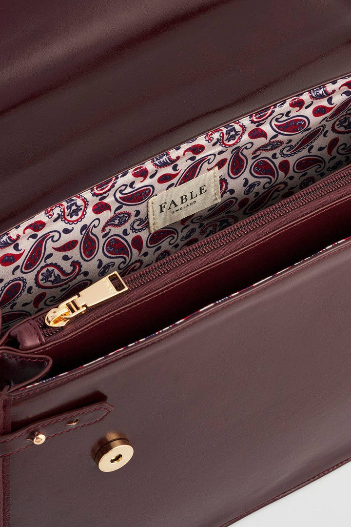 Close-up of a brown leather bag with a paisley patterned strap, featuring the brand 'Fable'.