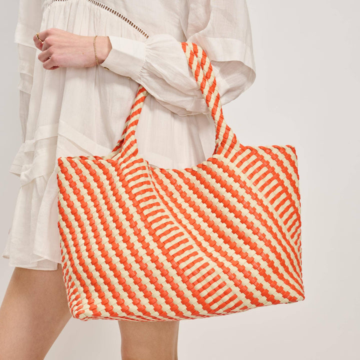 Person holding a red and white striped bag against a plain background
