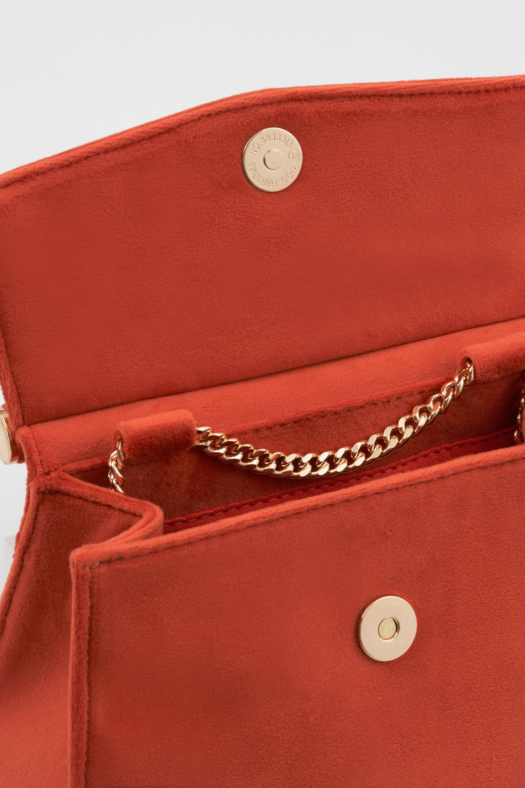 Red handbag with gold chain handle and decorative buttons on a light gray background