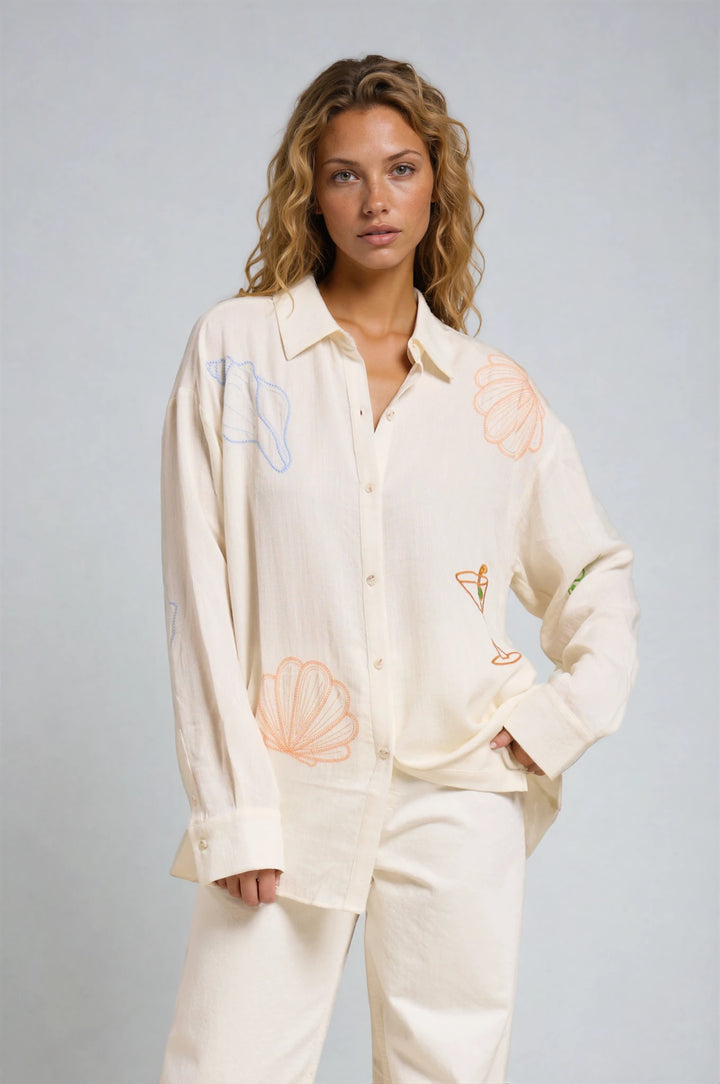 Woman wearing a cream-colored shirt with abstract designs on a gray background