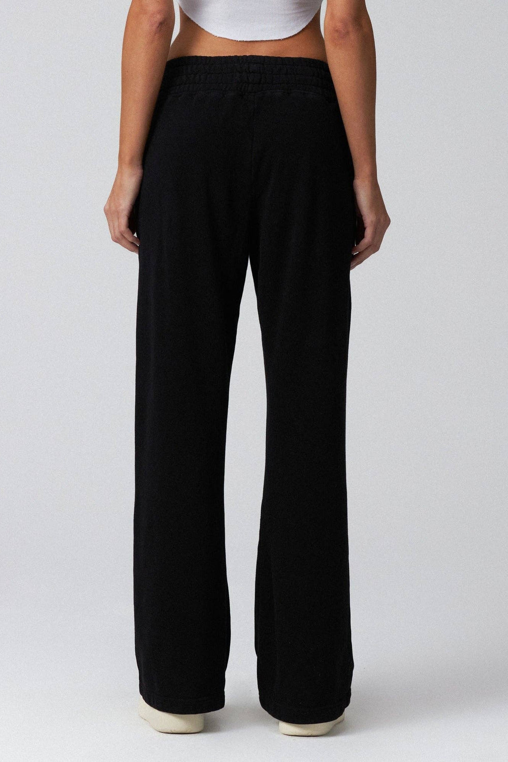 Person wearing black wide-leg pants on a plain background
