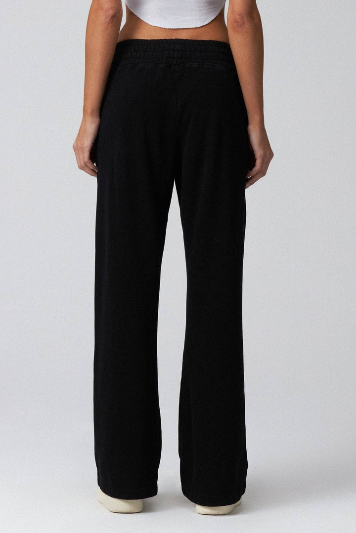 Person wearing black wide-leg pants on a plain background