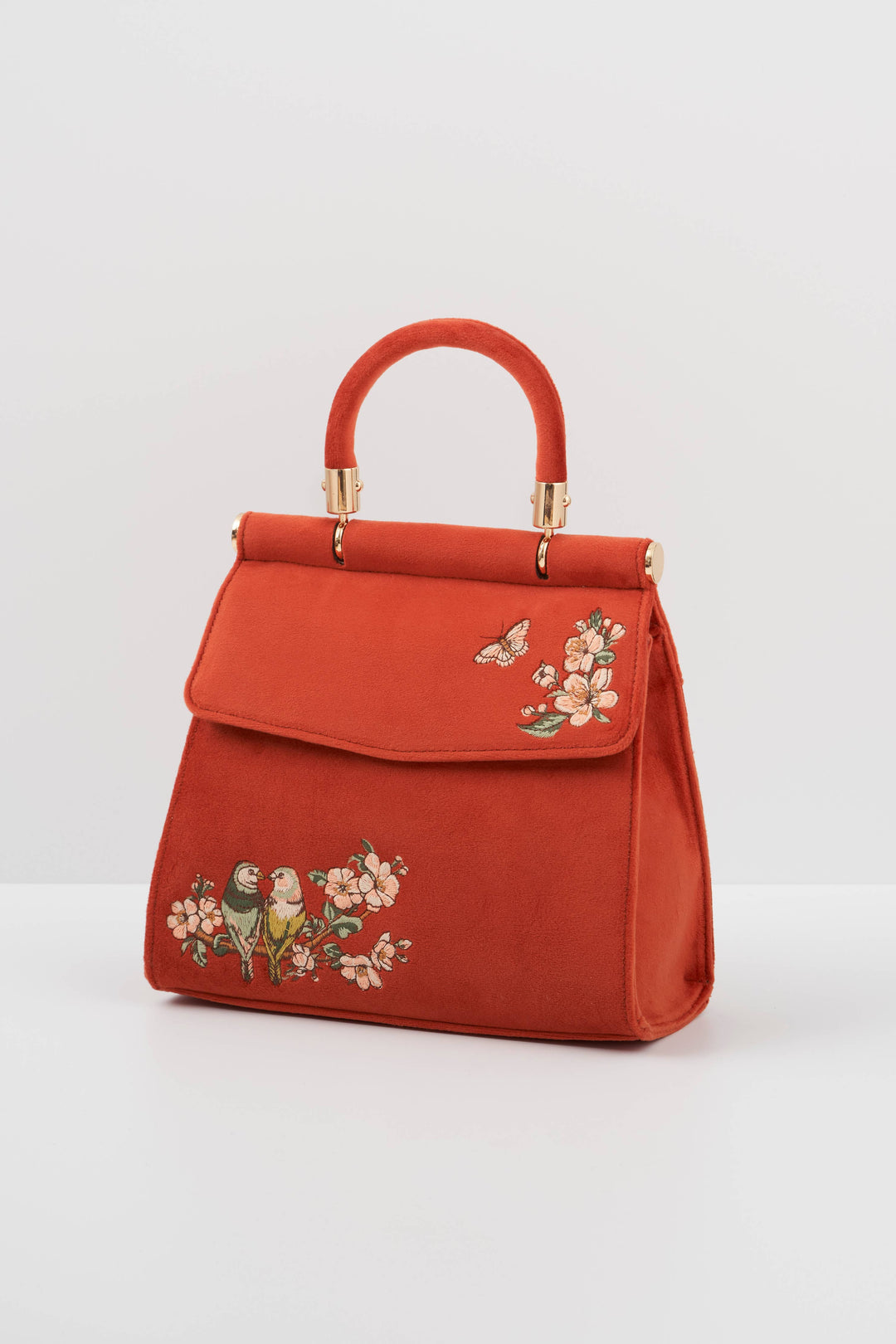 Red handbag with floral and bird embroidery on a light gray background
