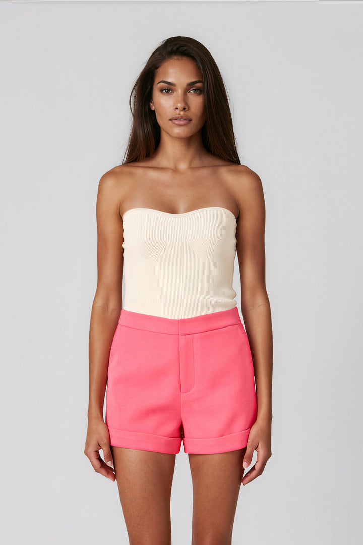 Woman wearing pink high-waisted tailored shorts with cuffed hem