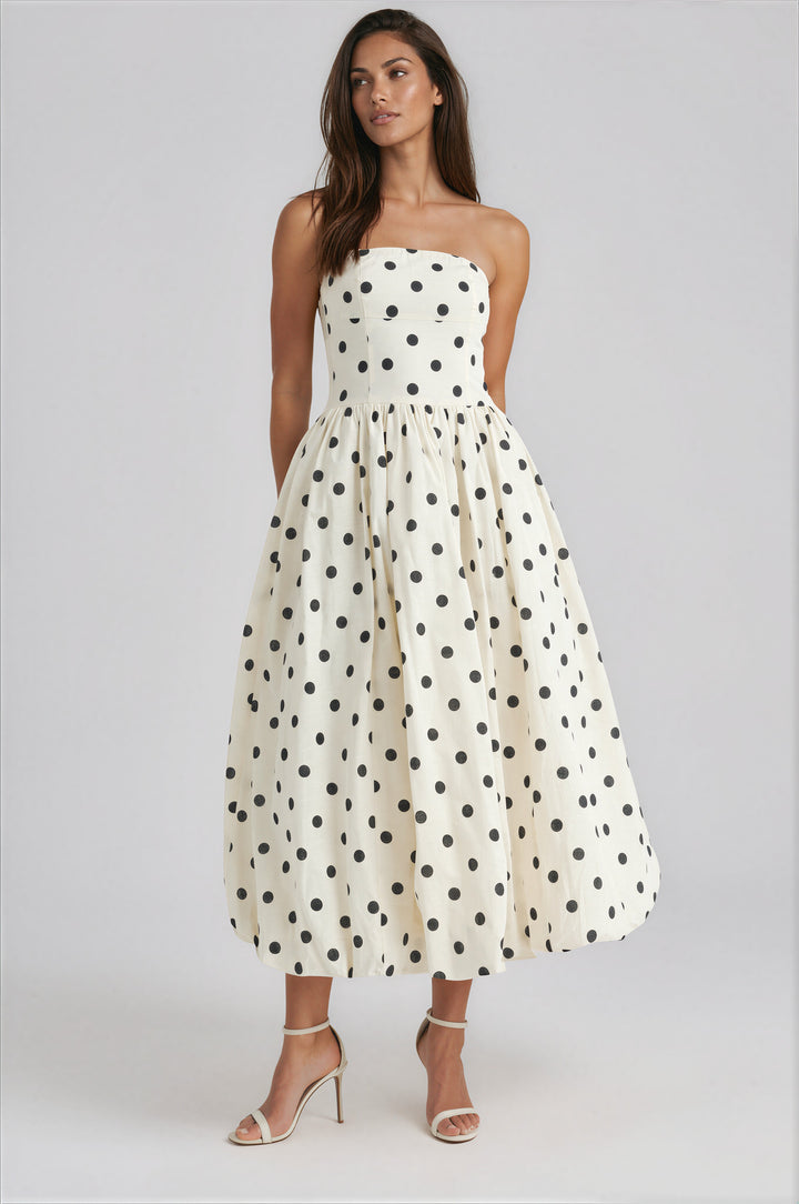 Woman wearing a strapless polka dot dress on a white background