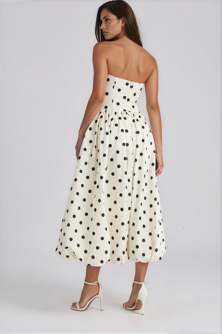 Woman wearing a strapless polka dot dress on a white background