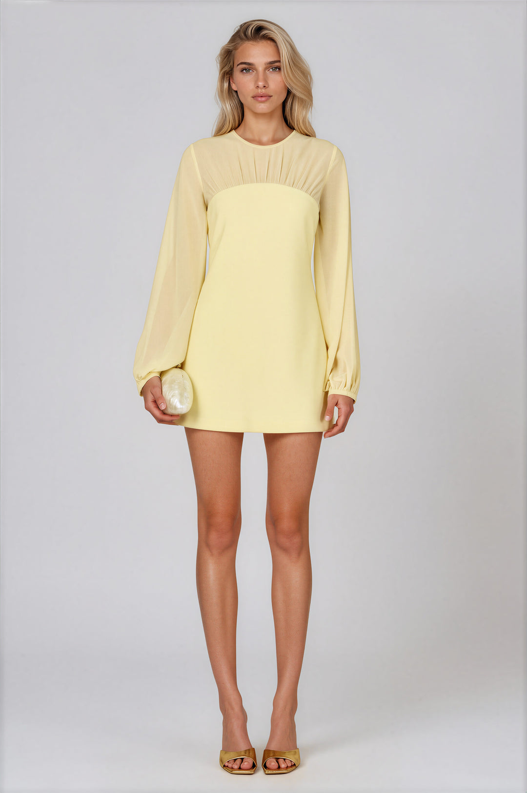 Woman wearing pale yellow mini dress with sheer chiffon yoke and long balloon sleeves