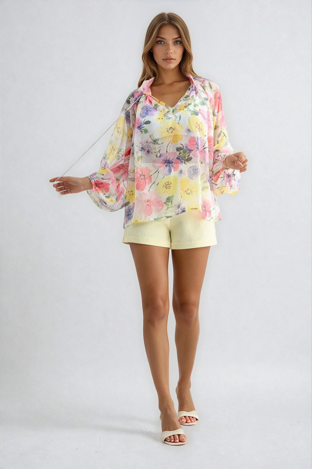 Woman wearing a floral blouse and yellow shorts on a white background