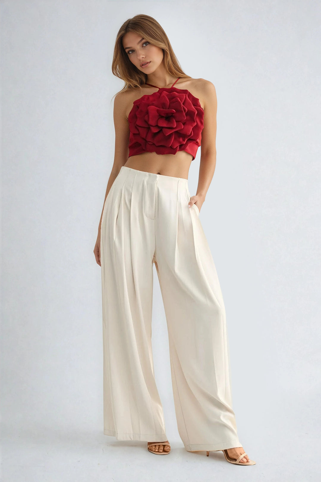 Woman wearing a red floral top and white pants on a light gray background