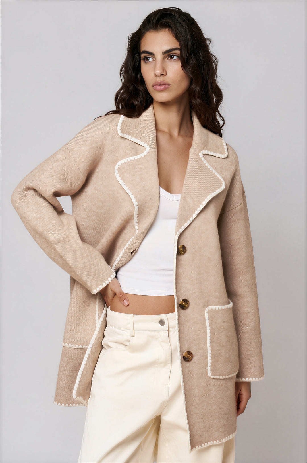Woman wearing beige button-front sweater jacket with contrast whipstitch trim and lapel collar