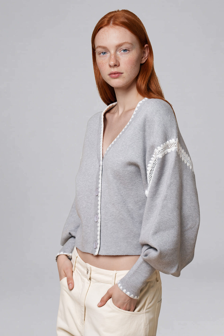 Grey cropped cardigan with white lace trim and voluminous sleeves, back view
