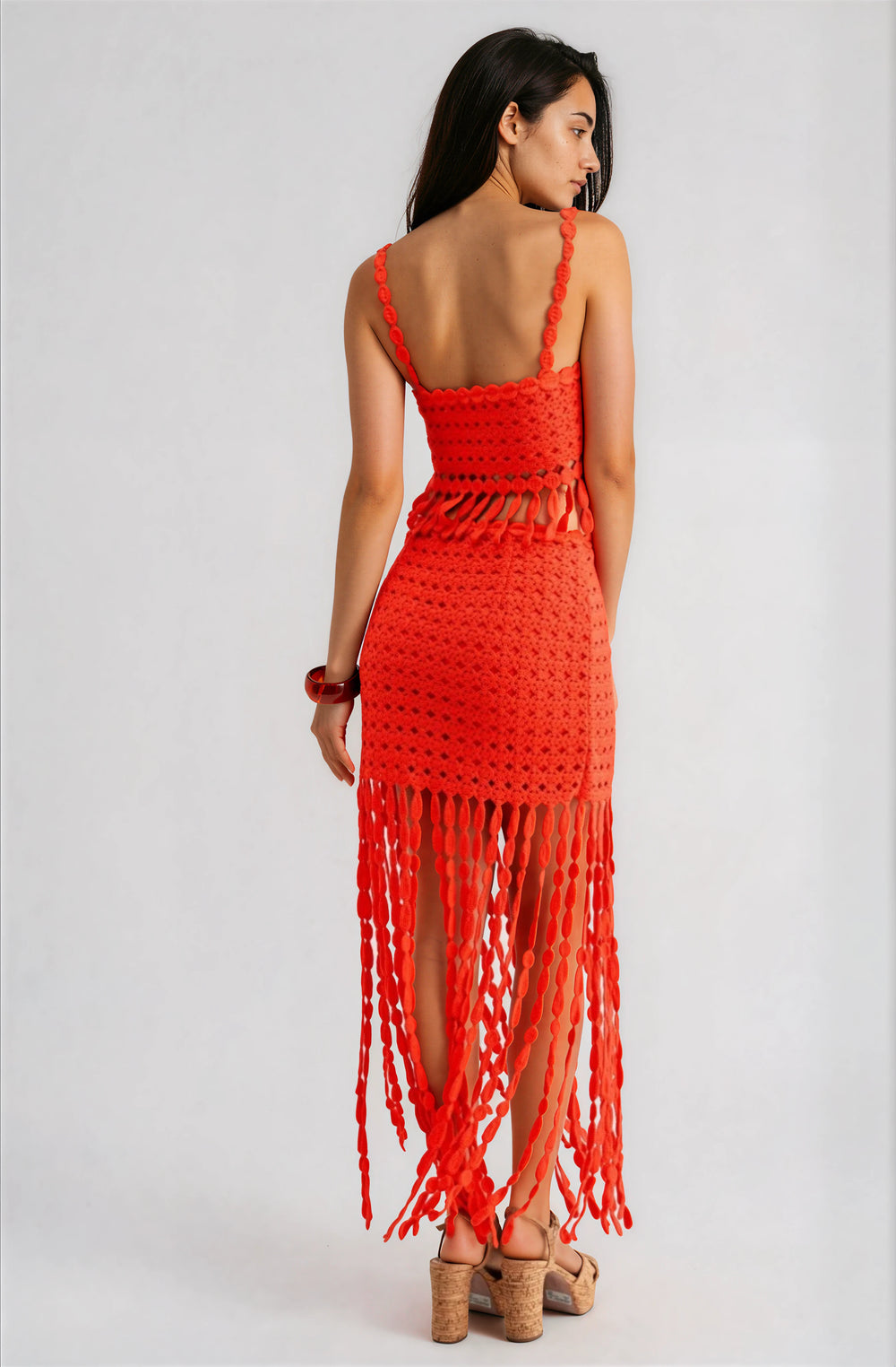 Woman wearing a red two piece crochet skirt set with fringe detail