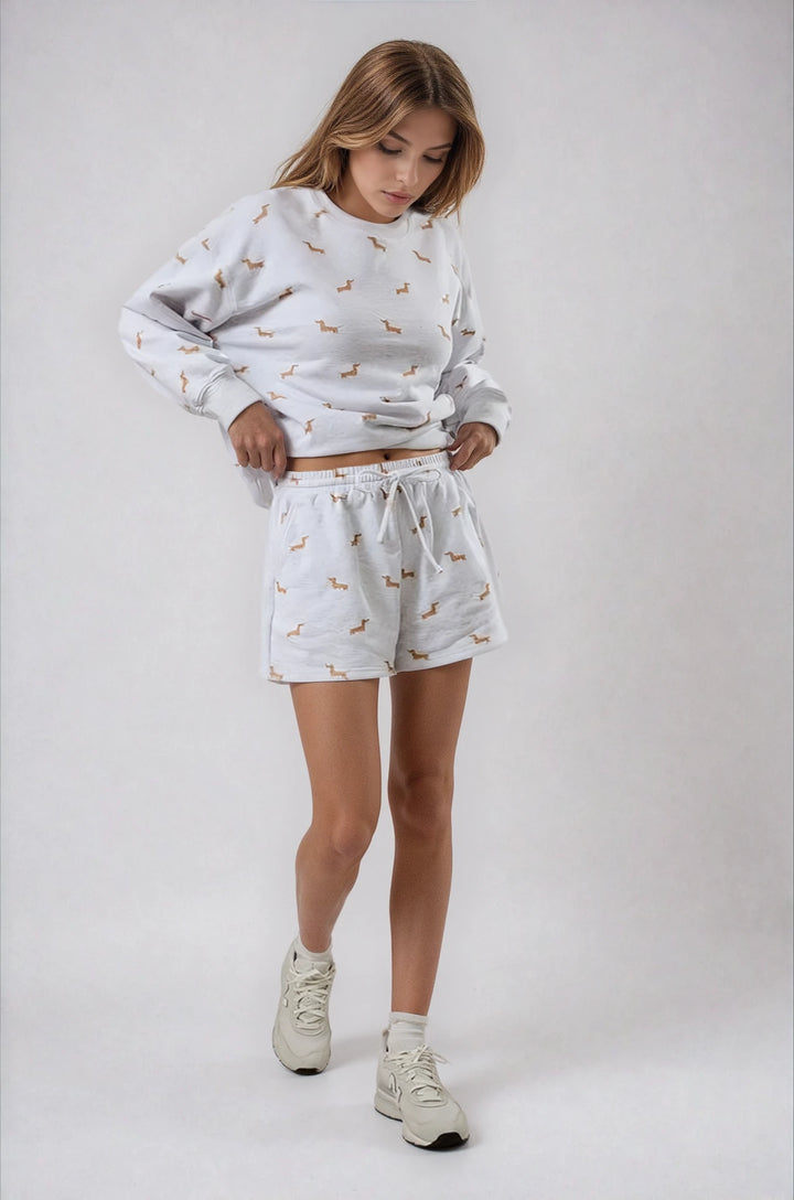 Young girl wearing a matching sweatshirt and shorts set with a pattern on a white background