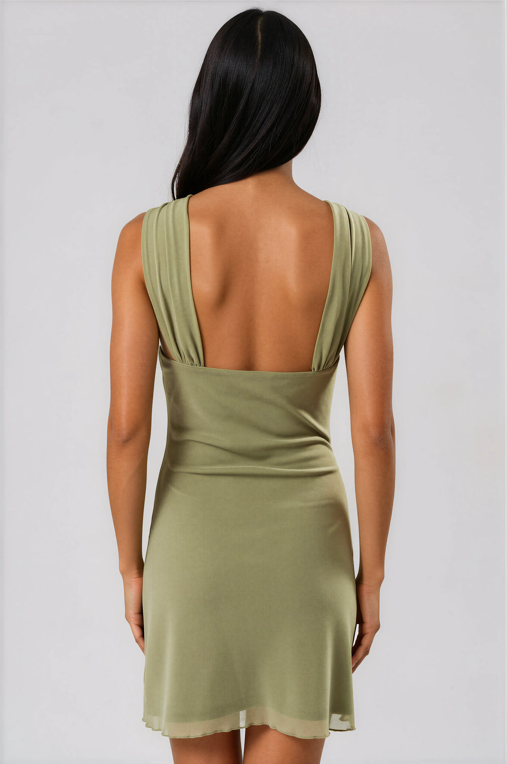 Green dress with open back worn by a person on a plain background