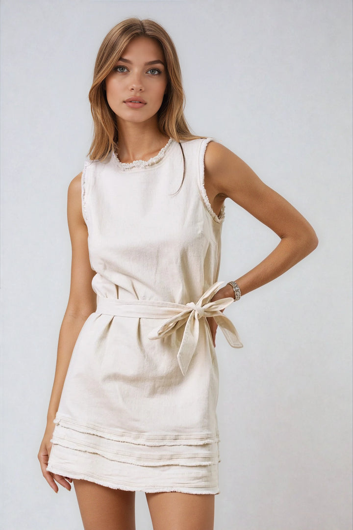 Woman wearing a white dress with a belt on a plain background