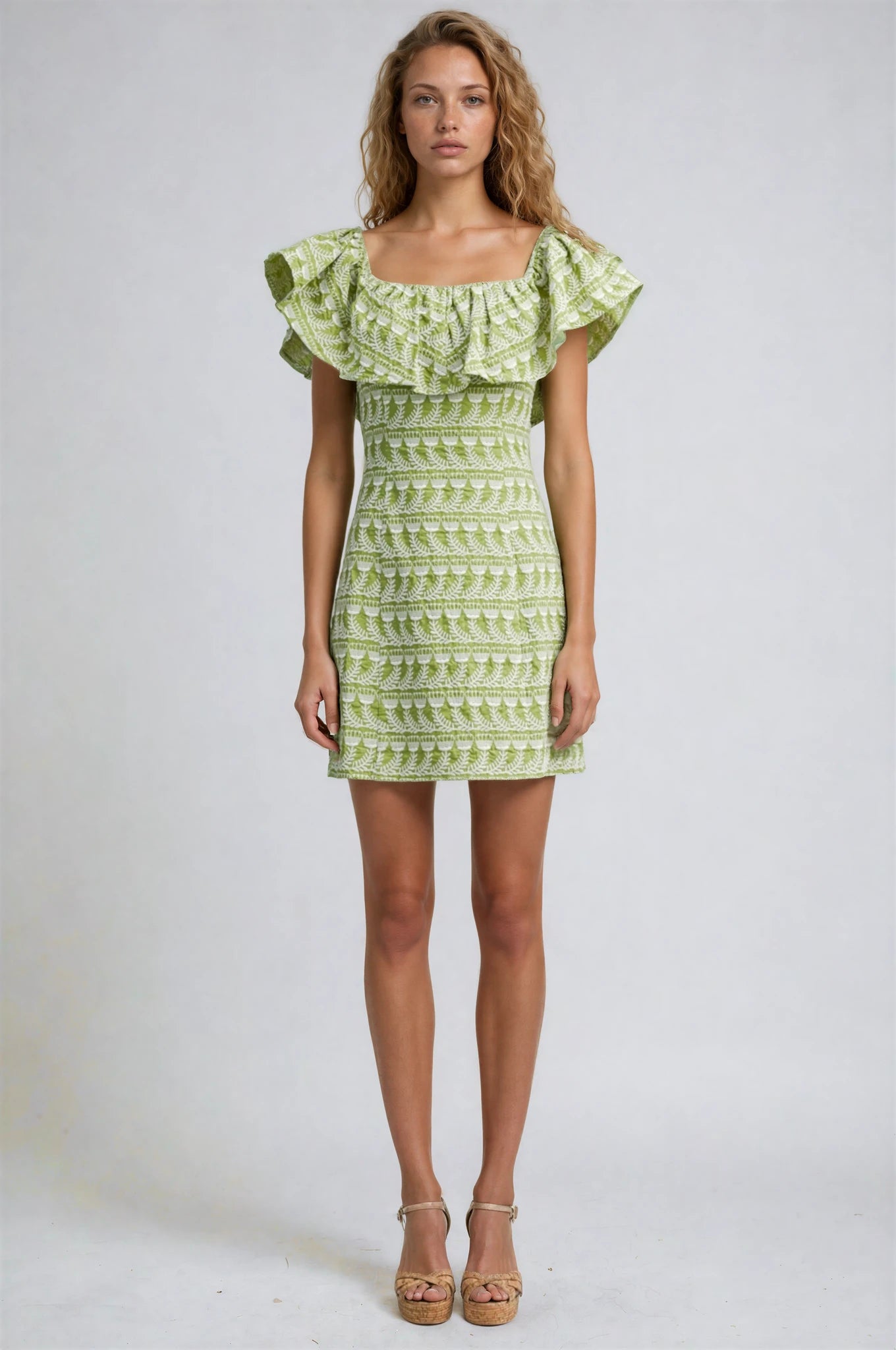 Woman wearing a green patterned dress on a white background