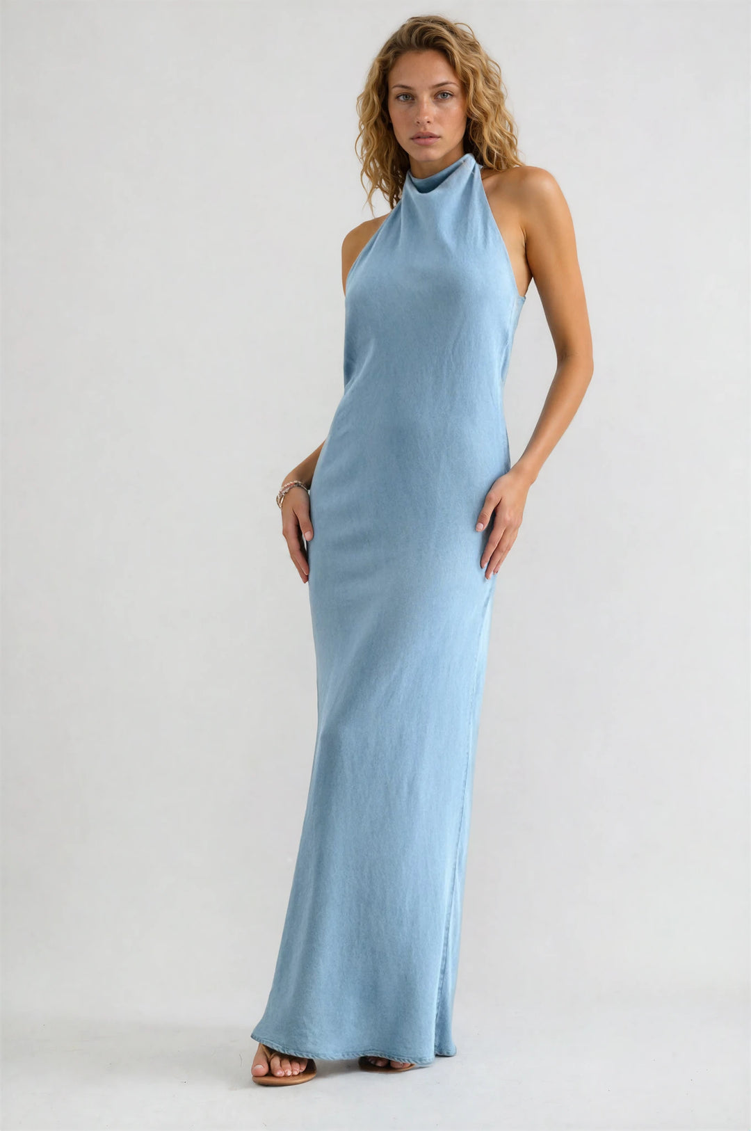 Woman wearing a light blue halter neck dress on a white background