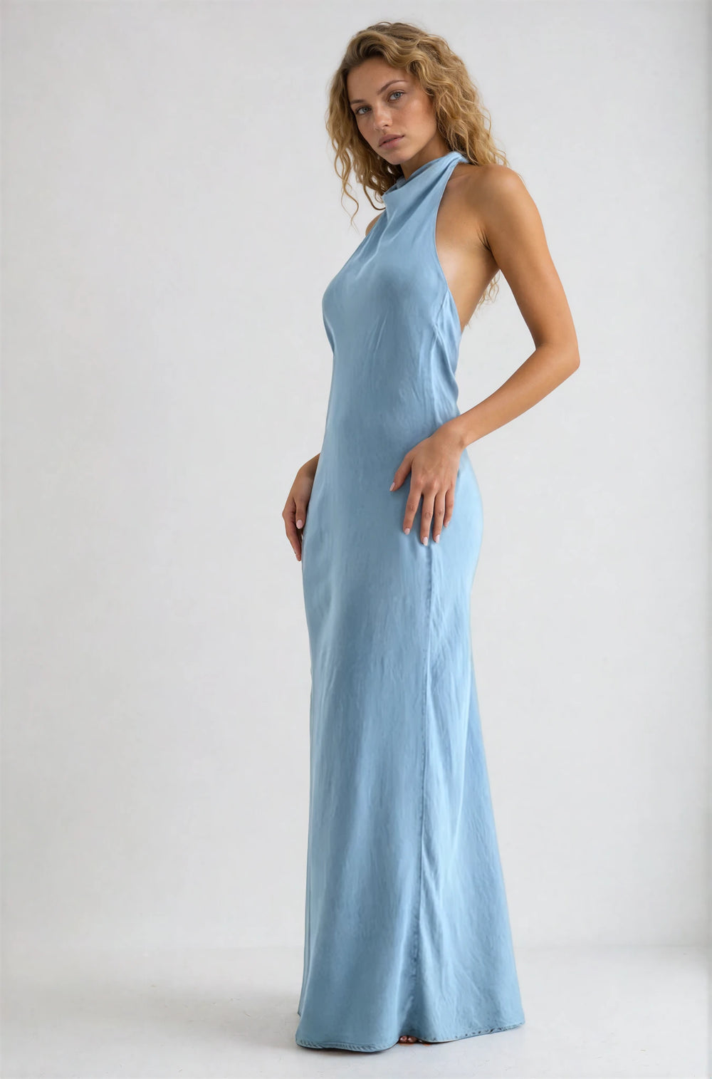 Woman wearing a light blue halter neck dress on a white background