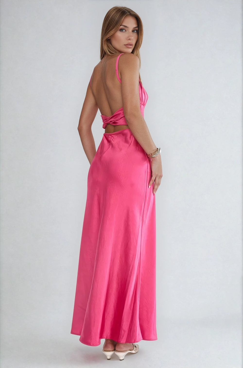 Woman wearing a pink dress with a cutout back on a white background