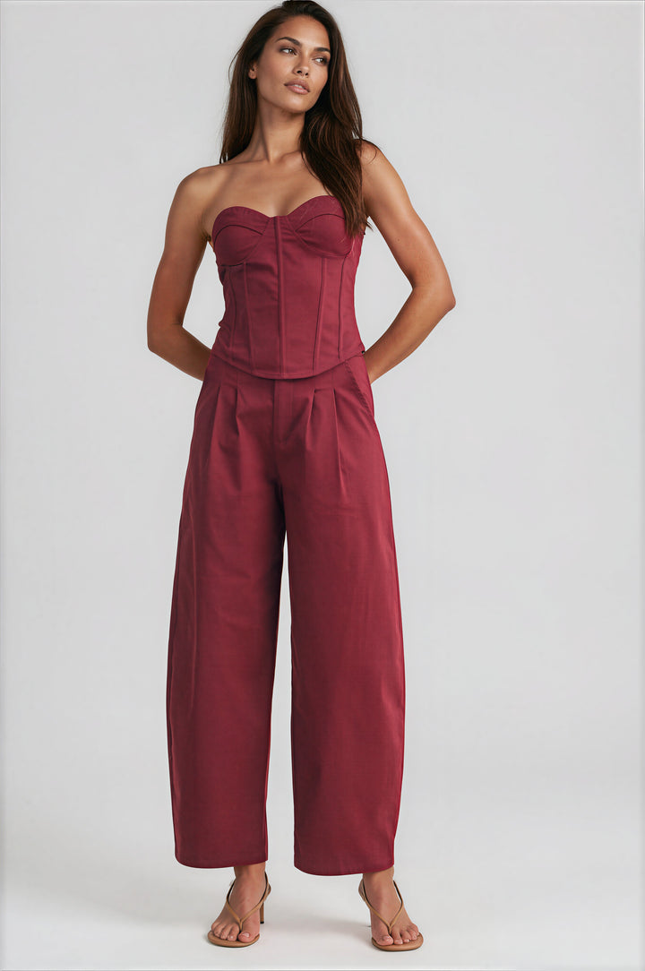 Woman wearing burgundy strapless corset top and high-waisted wide-leg pants set