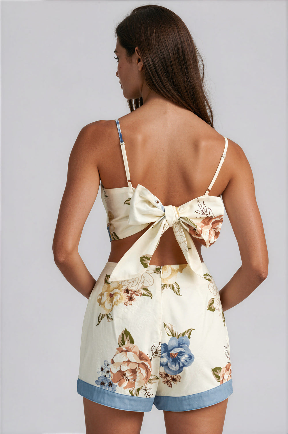 Back view of the Honey Floral Skort Set showing the open back cami top with an oversized self-tie bow detail in blue floral print on cream.