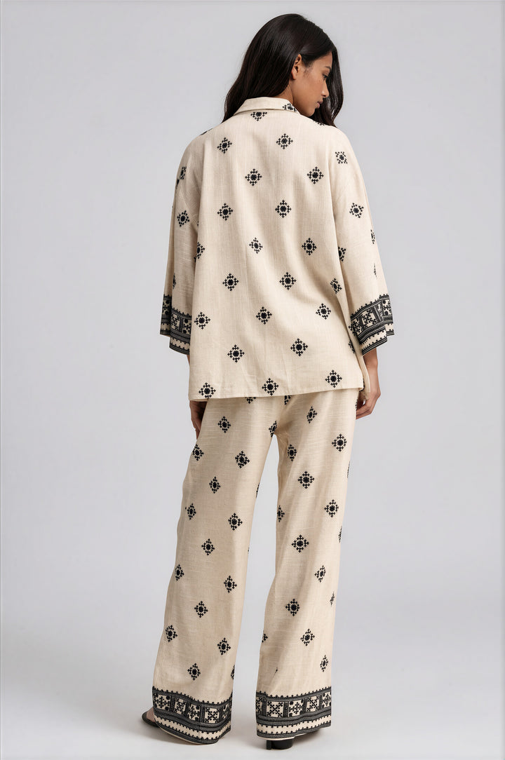 Back view of cream embroidered wide leg pants set with black border trim at the cuffs and hem
