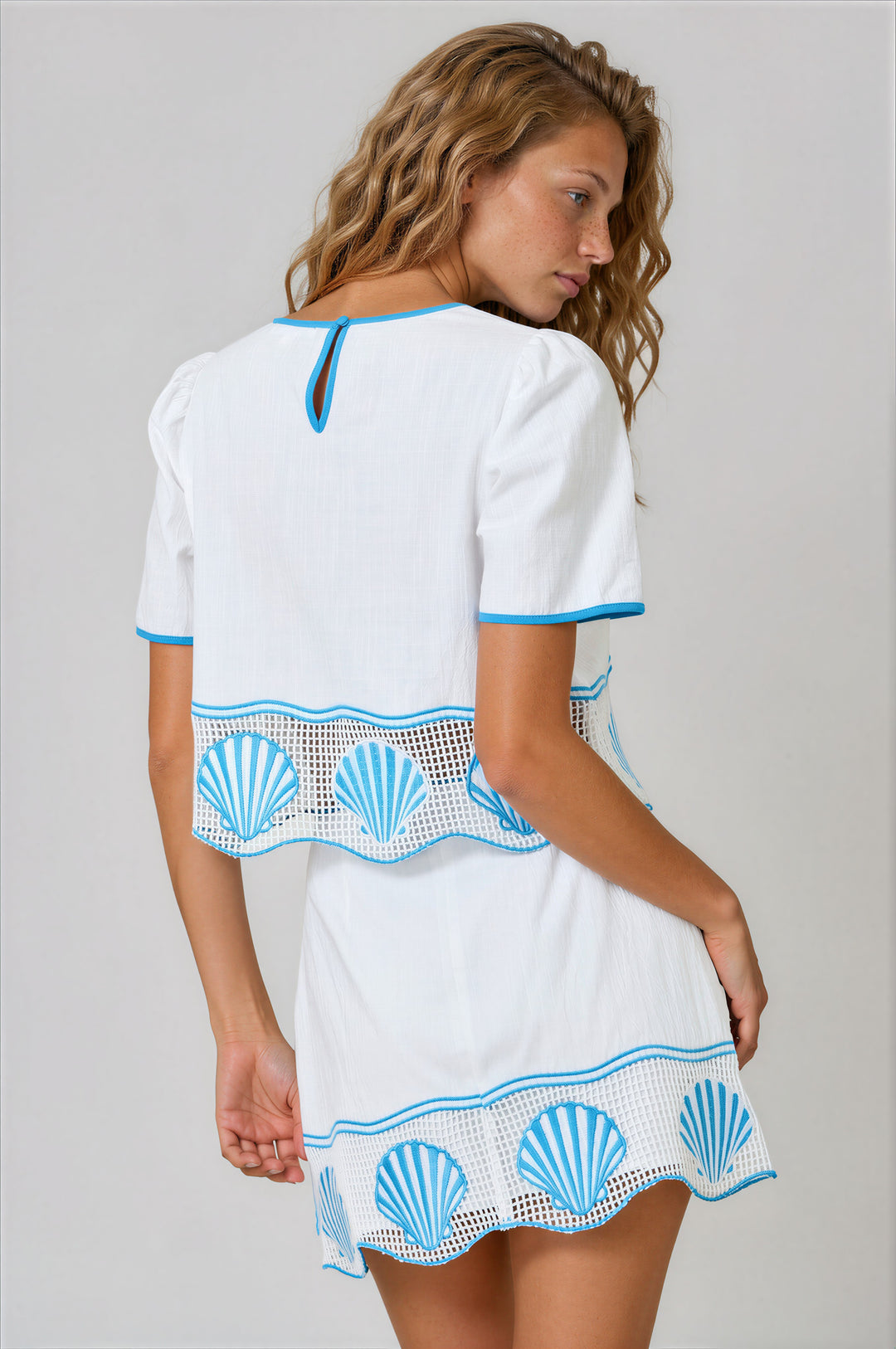 woman wearing white and blue matching skirt set with shell embroidered design