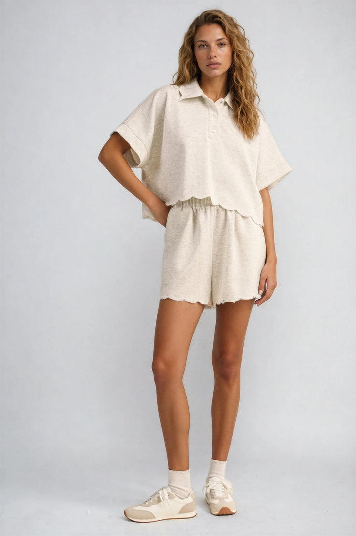 Woman wearing a beige outfit with shorts and a shirt on a plain background