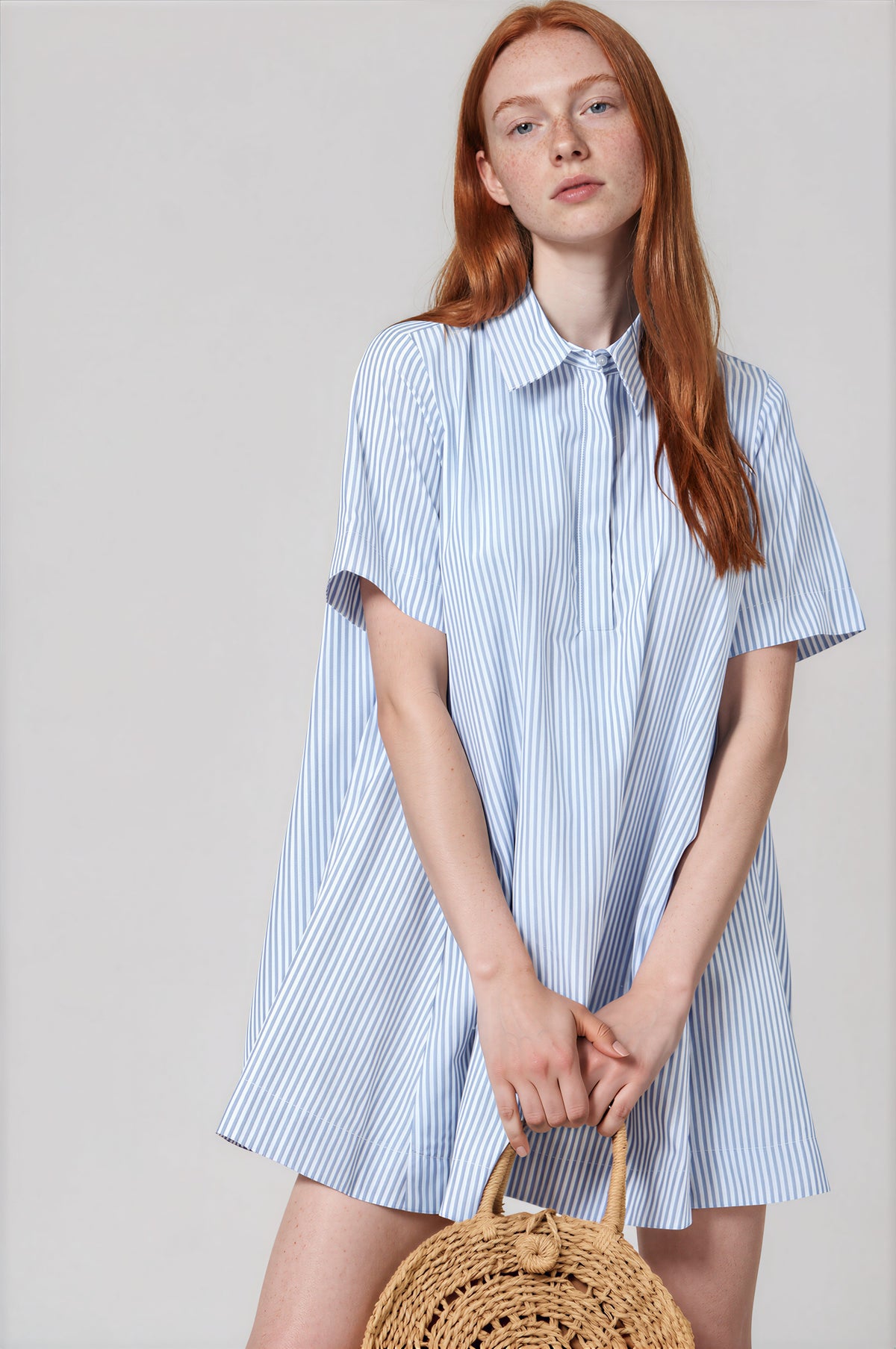 Woman wearing blue and white striped short sleeve collared A-line shirt dress