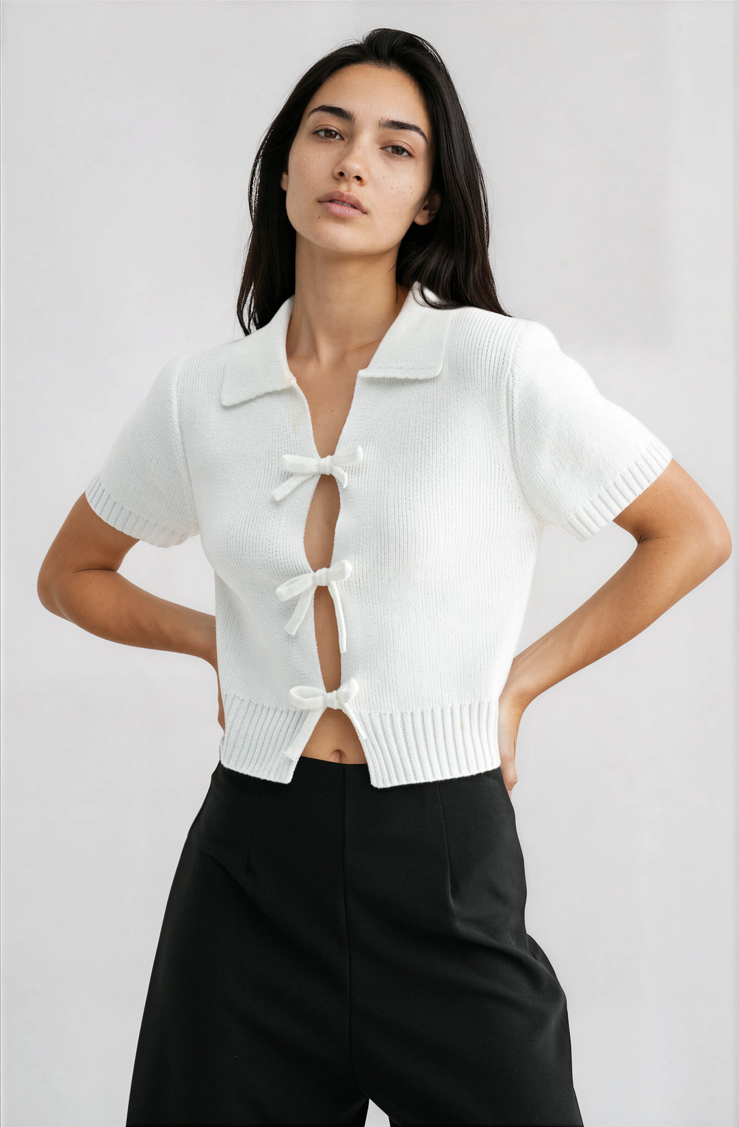 woman wearing white short sleeve knit top with bow cutout detail