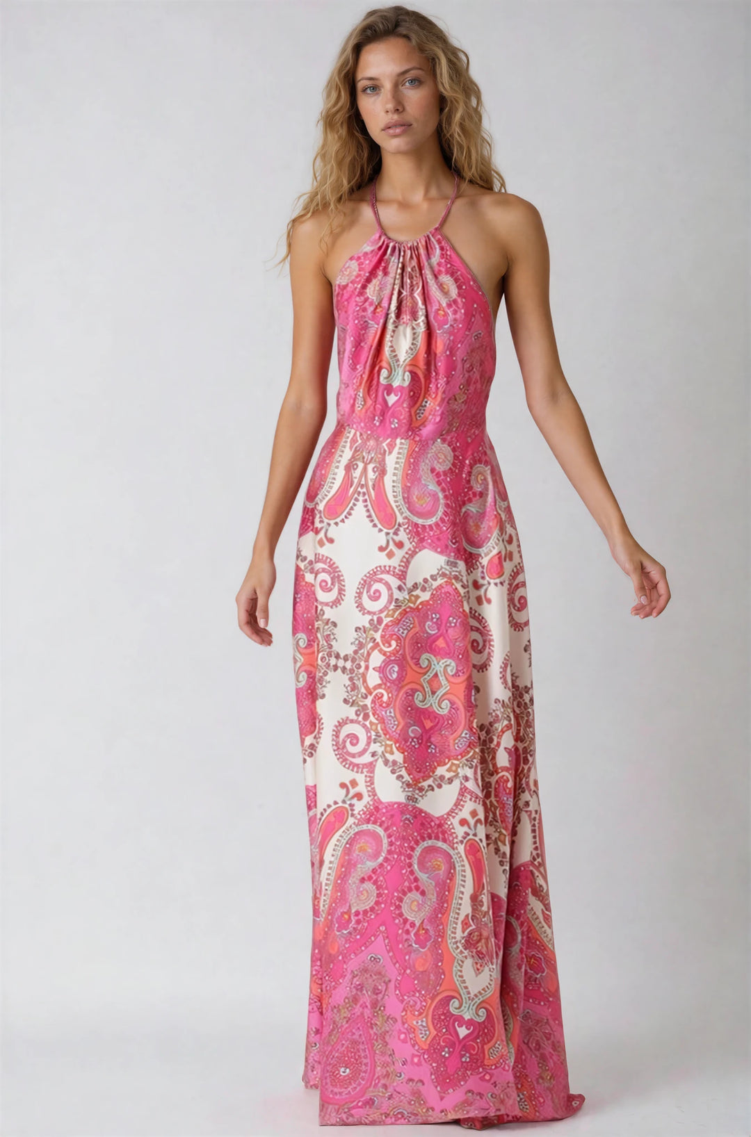 Woman wearing a pink and white patterned halter neck dress on a plain background