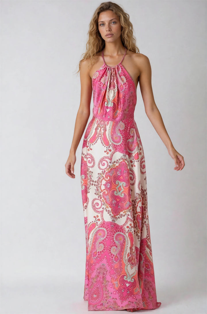 Woman wearing a pink and white patterned halter neck dress on a plain background