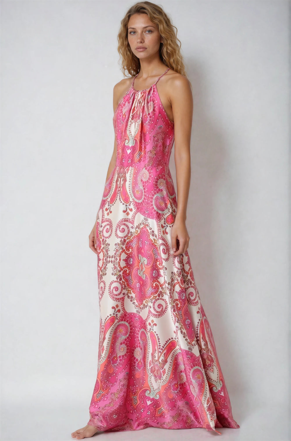 Woman wearing a pink and white patterned dress on a plain background