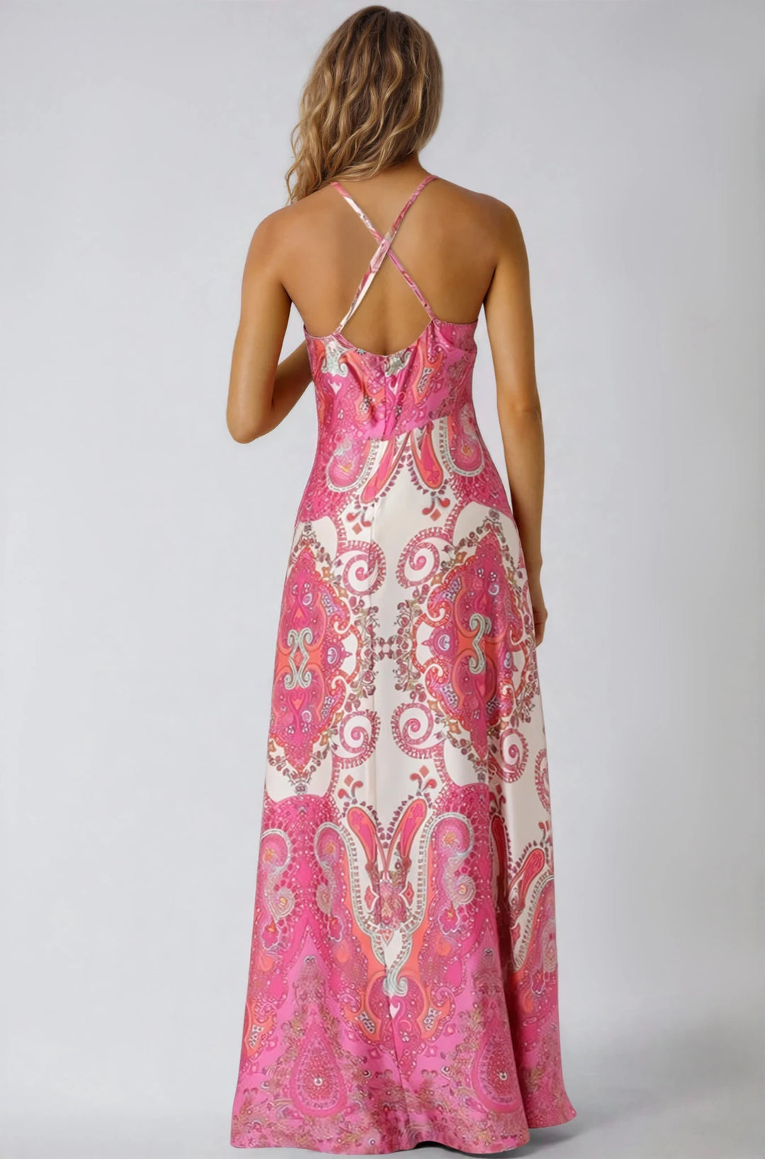 Woman wearing a pink and white patterned maxi dress on a plain background