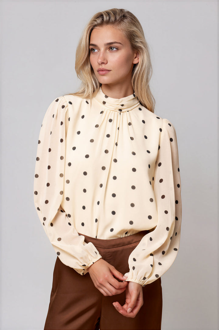 Cream polka dot blouse with high mock neckline and long puff sleeves, front view