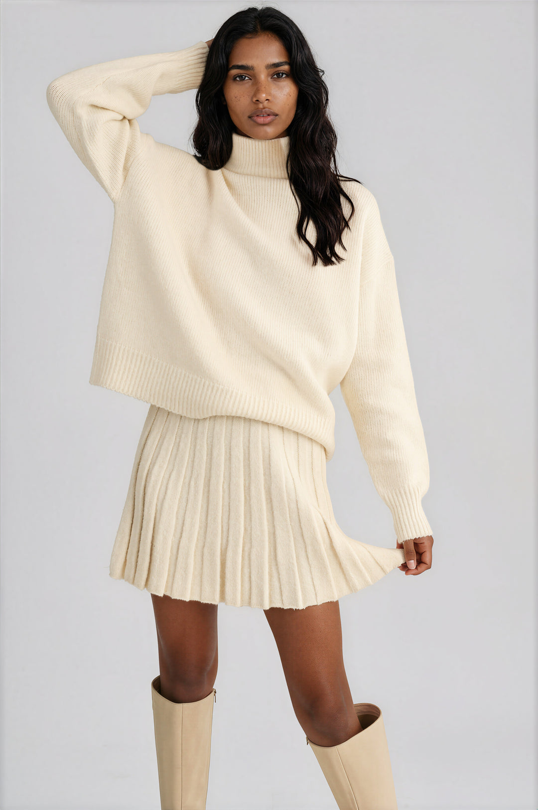 Cream knit set with an oversized turtleneck sweater and pleated mini skirt, front view