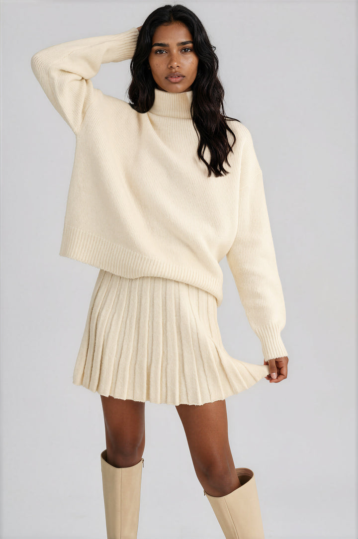 Cream knit set with an oversized turtleneck sweater and pleated mini skirt, front view