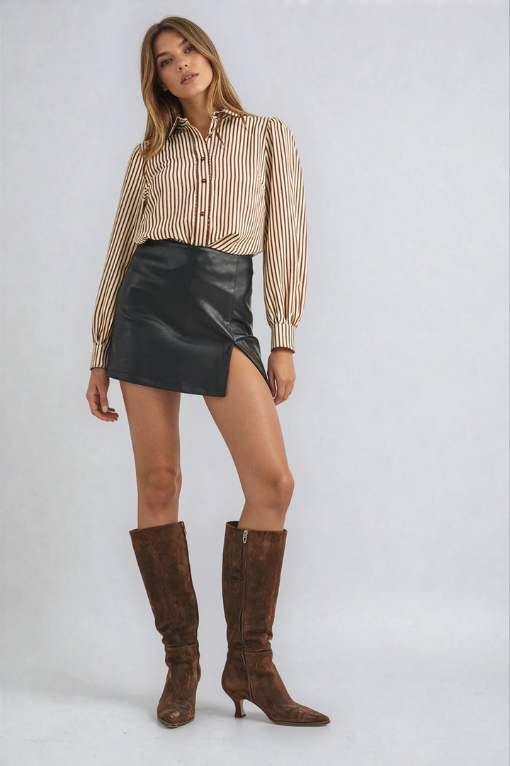 Woman wearing a striped shirt, black leather skirt, and brown knee-high boots on a white background