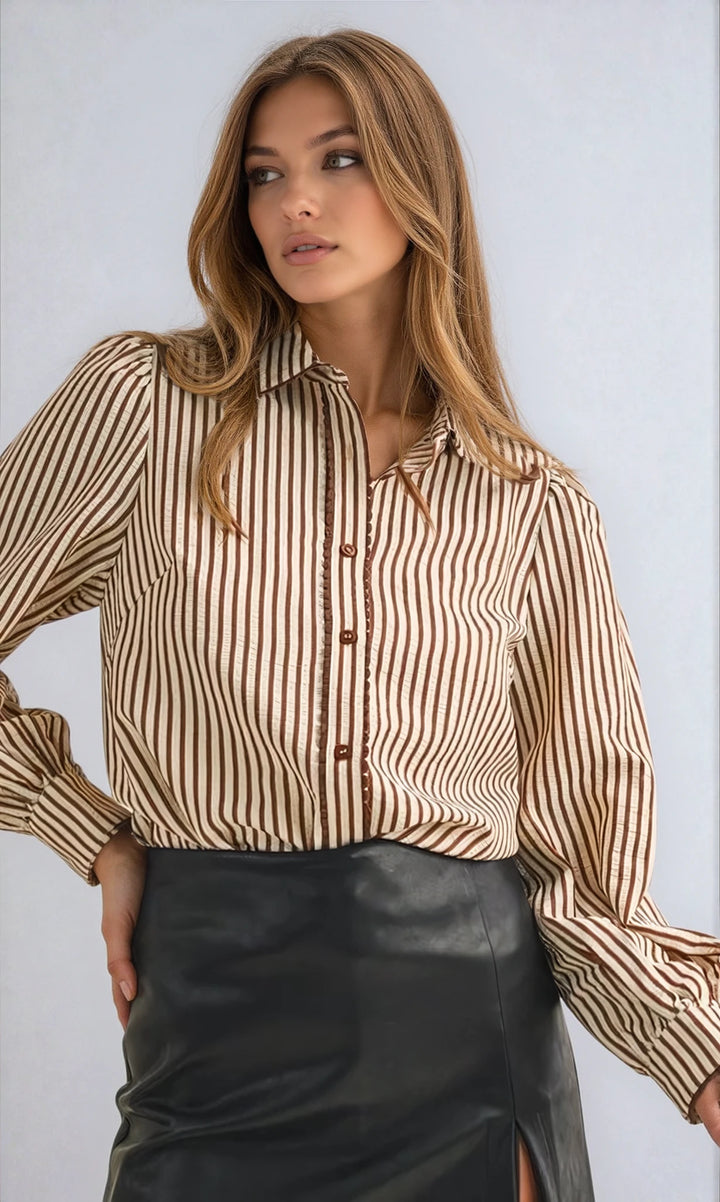 Woman wearing a striped shirt and black leather skirt against a light background