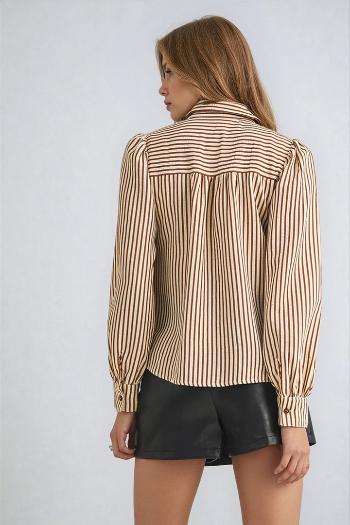 Woman wearing a striped blouse and black shorts on a plain background