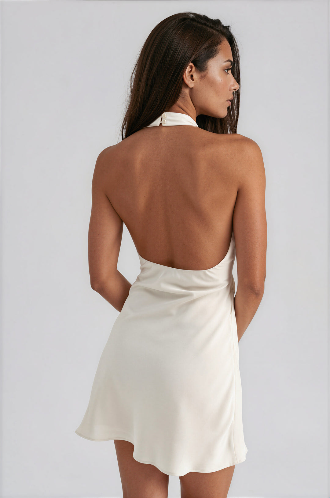 Back view of cream satin halter mini dress with open back and halter button closure