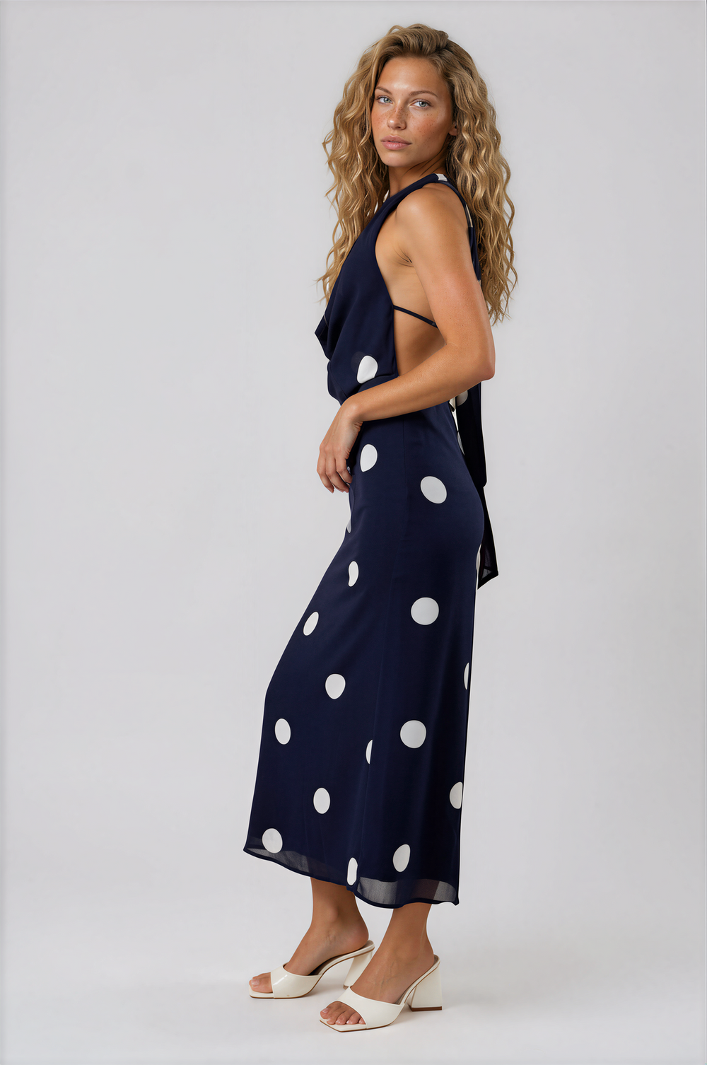 Woman wearing navy blue polka dot halter maxi dress