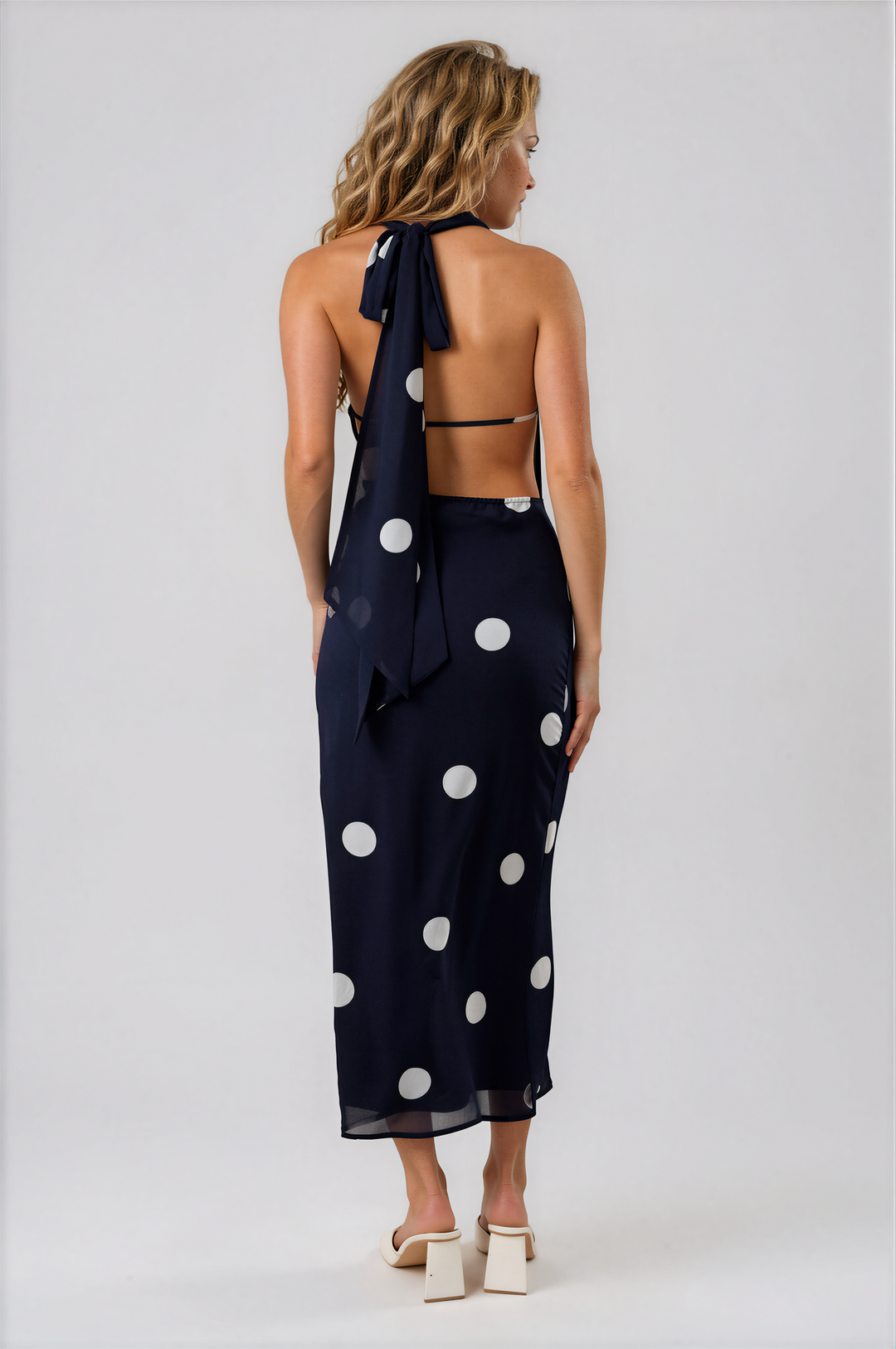 Woman wearing navy blue polka dot halter maxi dress