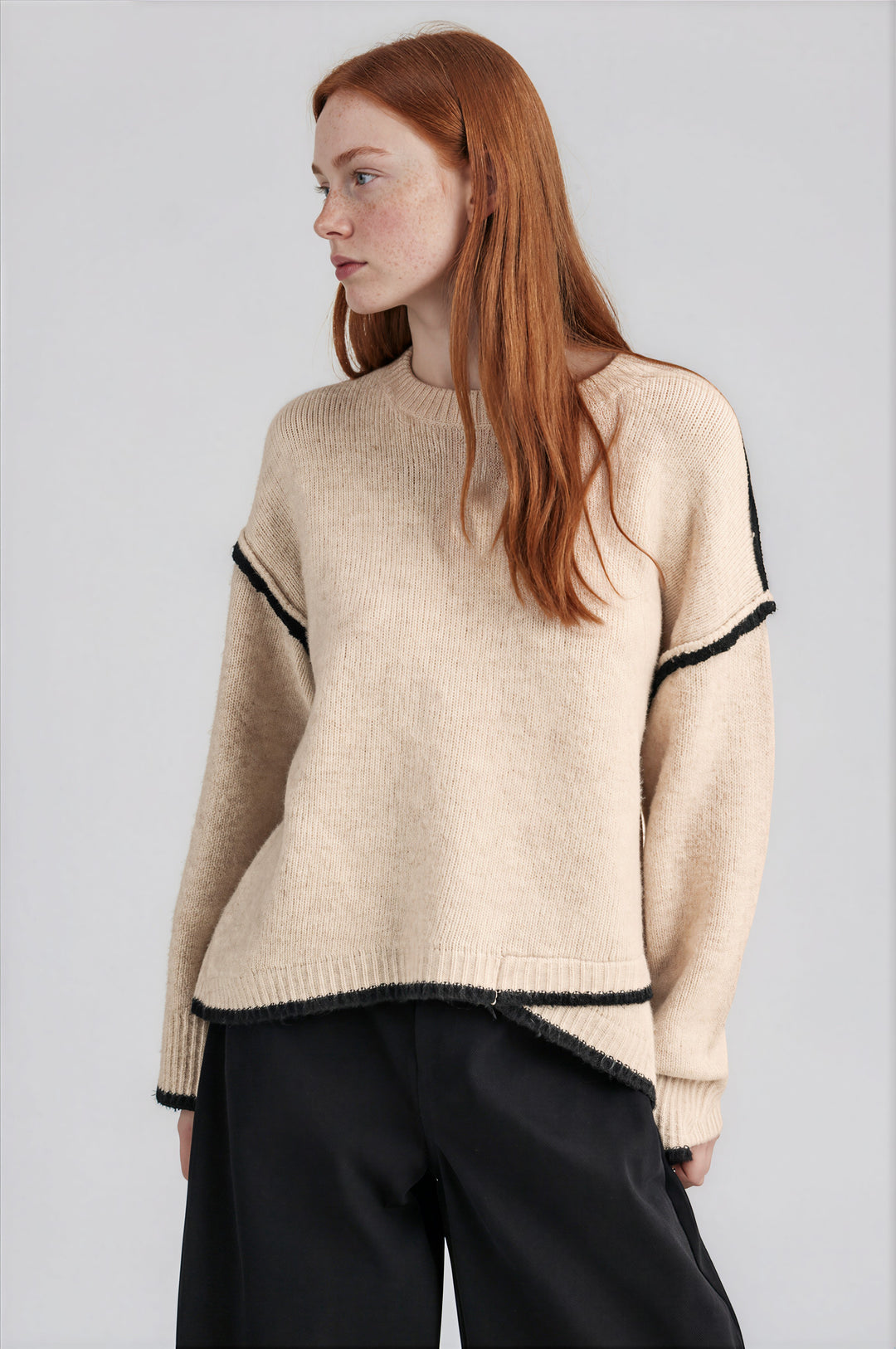Cream knit sweater with black contrast trim and exposed seams, front view