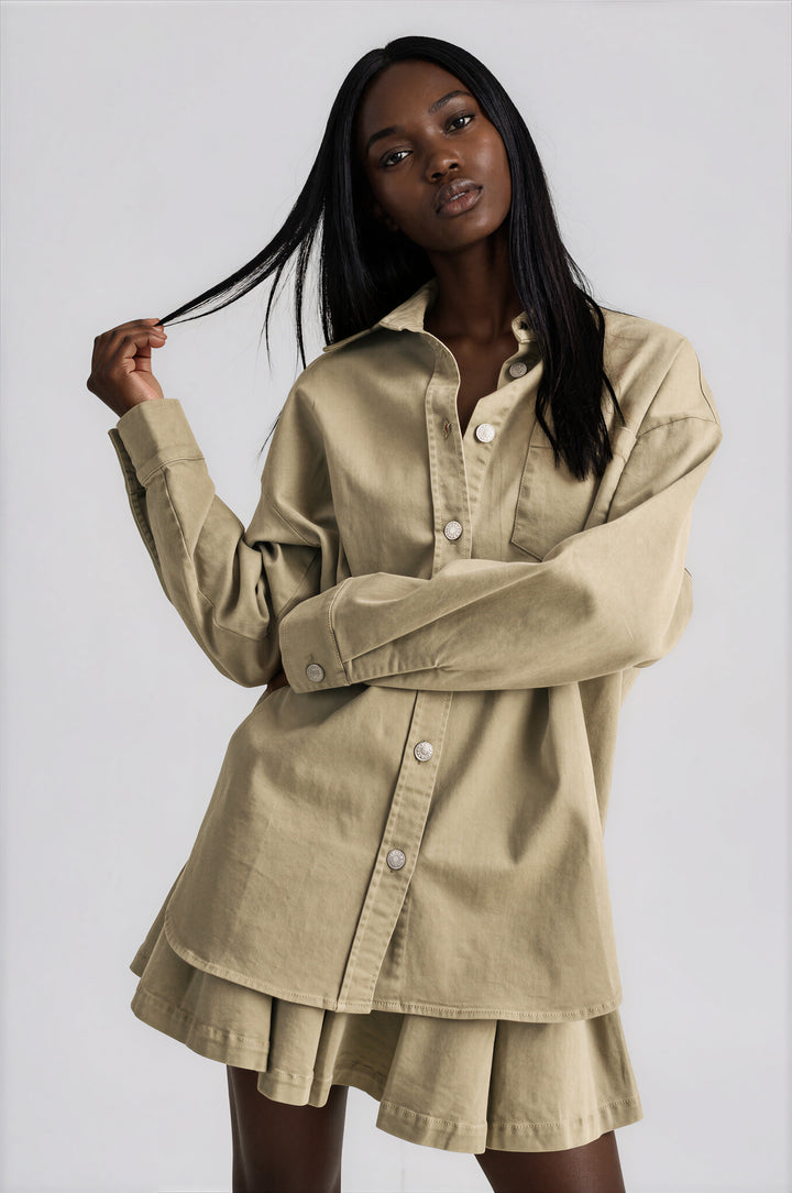 Olive cotton set with an oversized button-down shirt and pleated mini skirt, front view