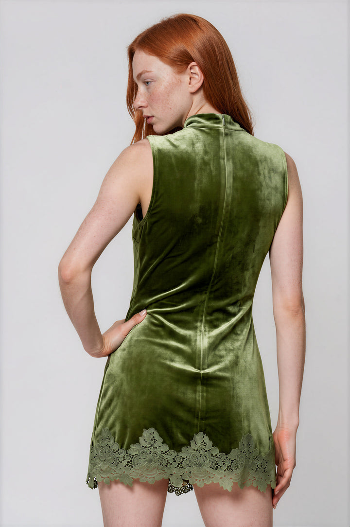 Woman wearing olive velvet mock neck bodycon mini dress with ruched sides