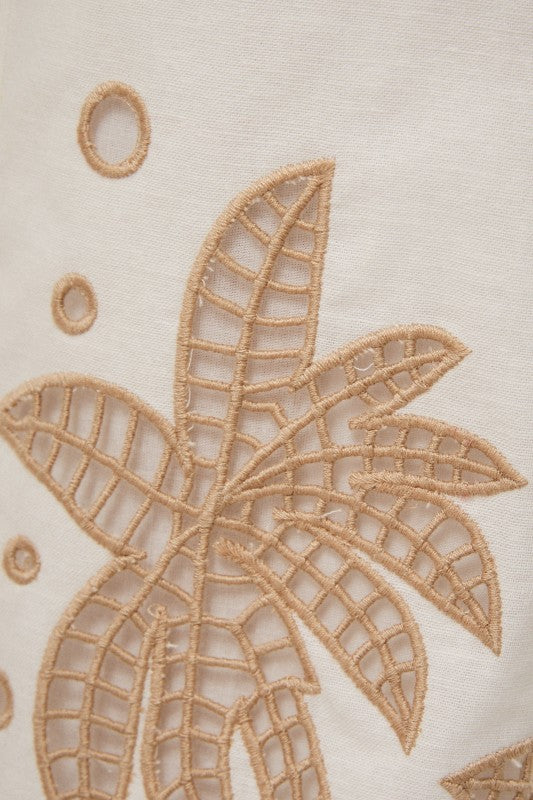 Close-up of a embroidered palm tree design on fabric.
