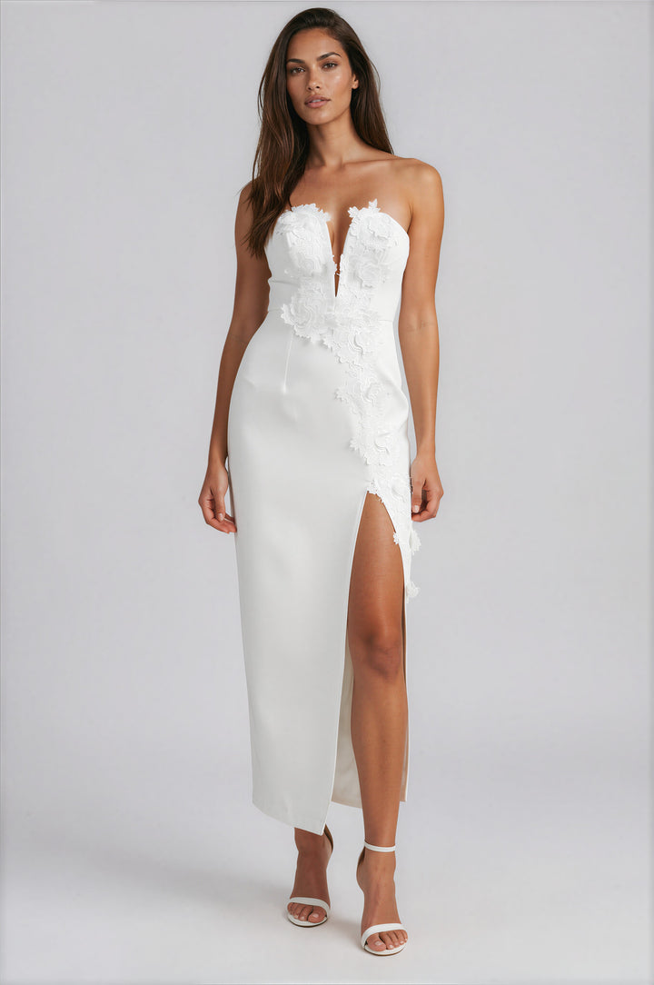 Woman wearing off-white strapless maxi dress with floral lace appliqué bodice and front slit