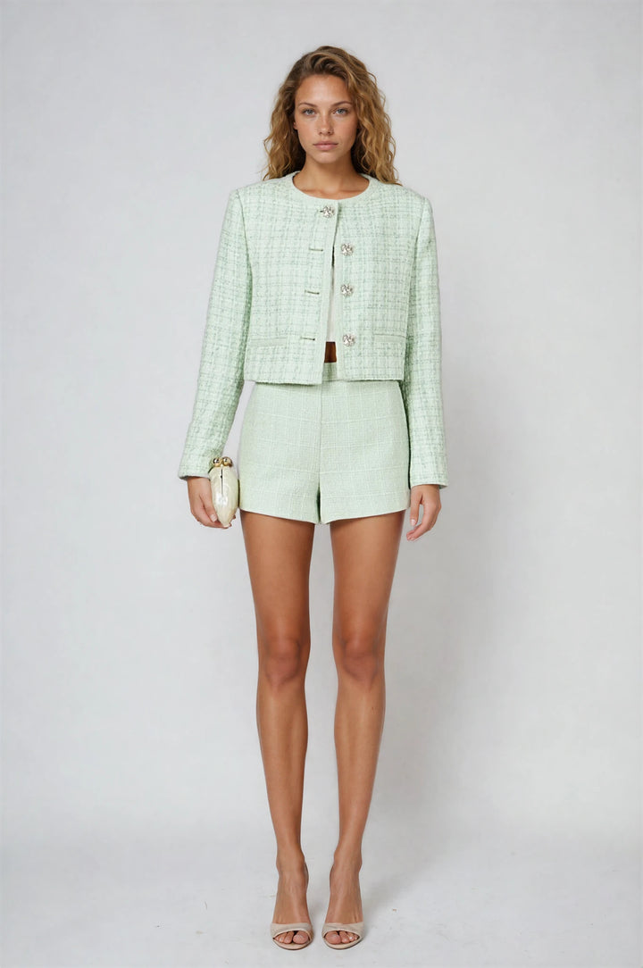 Woman wearing a light green suit with shorts on a white background